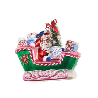 Decorative Christmas ornament of Santa in a sleigh with presents and a tree.