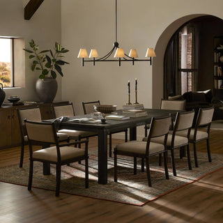 A warmly lit dining room with the Oman Dining Table, styled with modern decor and seating.