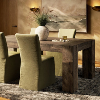 A stylish dining space featuring the Abaso Dining Table, complemented by plush green chairs and a contemporary setting.