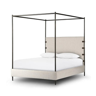 Angled side view of a queen-size canopy bed, featuring a boucle-upholstered headboard and a sturdy metal frame.