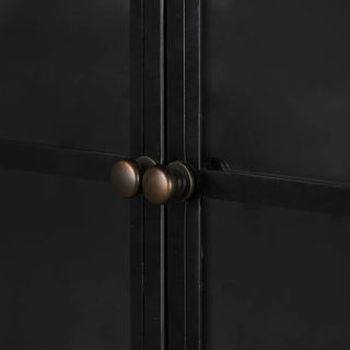 Close-up of the round brass knobs on the glass doors of the wide iron metal cabinet.