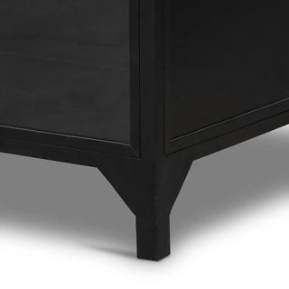 Close-up of the sturdy black iron legs of the wide metal cabinet.