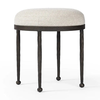 Angled perspective view of a hammered iron accent stool with an upholstered seat, highlighting its modern design.