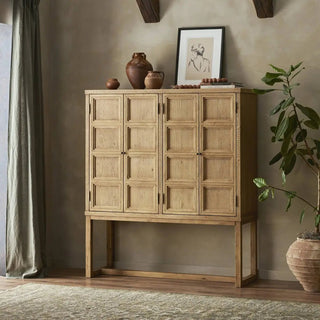 Worn oak cabinet styled in a rustic interior with ceramic vases and artwork on top.