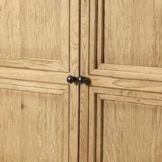 Detailed view of the worn oak cabinet's metal door knobs and panel design.