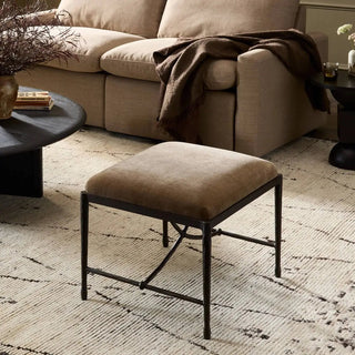 Art deco-inspired iron stool styled in a cozy living space with a neutral-toned couch and decor.