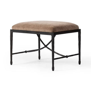 Angled view of an iron stool with a brown velvet seat and decorative iron base.