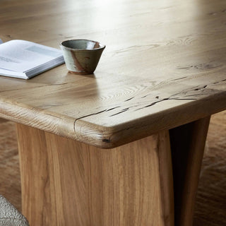 A modern yet rustic reclaimed French oak dining table with sculptural legs and a minimalist aesthetic.