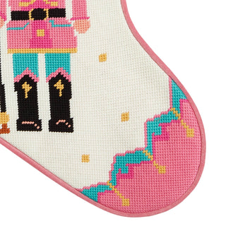 Cross-stitched design of a nutcracker character on fabric with pink border