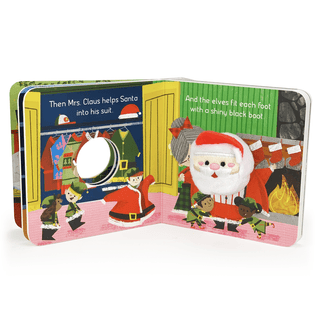 Children's book open to a page with Santa Claus and elves in a workshop setting.