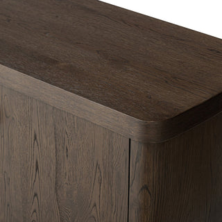 Detailed close-up of the rounded top corner of the rustic brown oak sideboard, emphasizing craftsmanship.