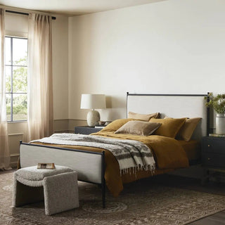 Queen-size upholstered bed styled in a warm, modern bedroom with cozy layered bedding and elegant decor.